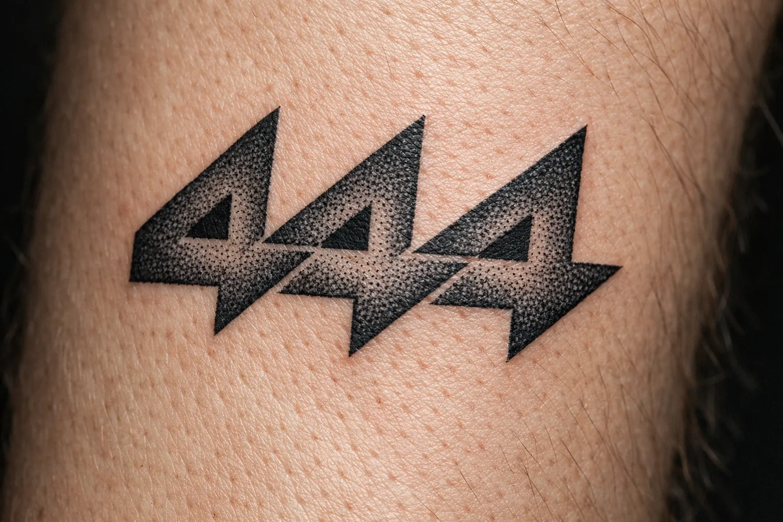 A close-up of a '444' tattoo in bold black ink on human skin.