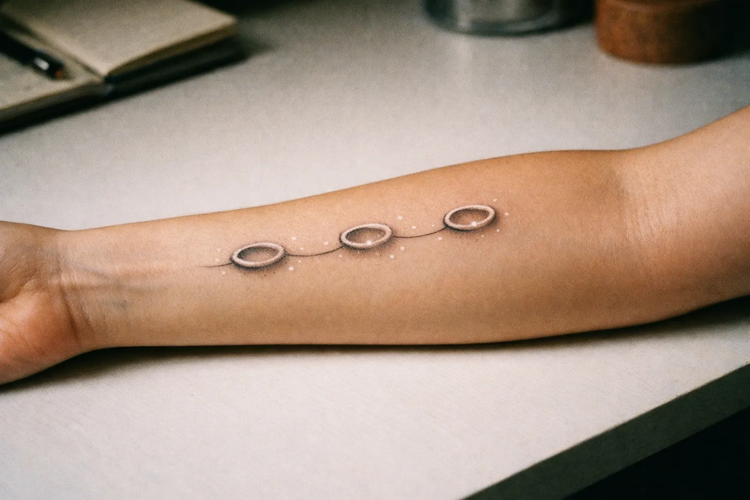 Three small circular halos along the inner forearm connected by a delicate line, symbolizing angel numbers without digits
