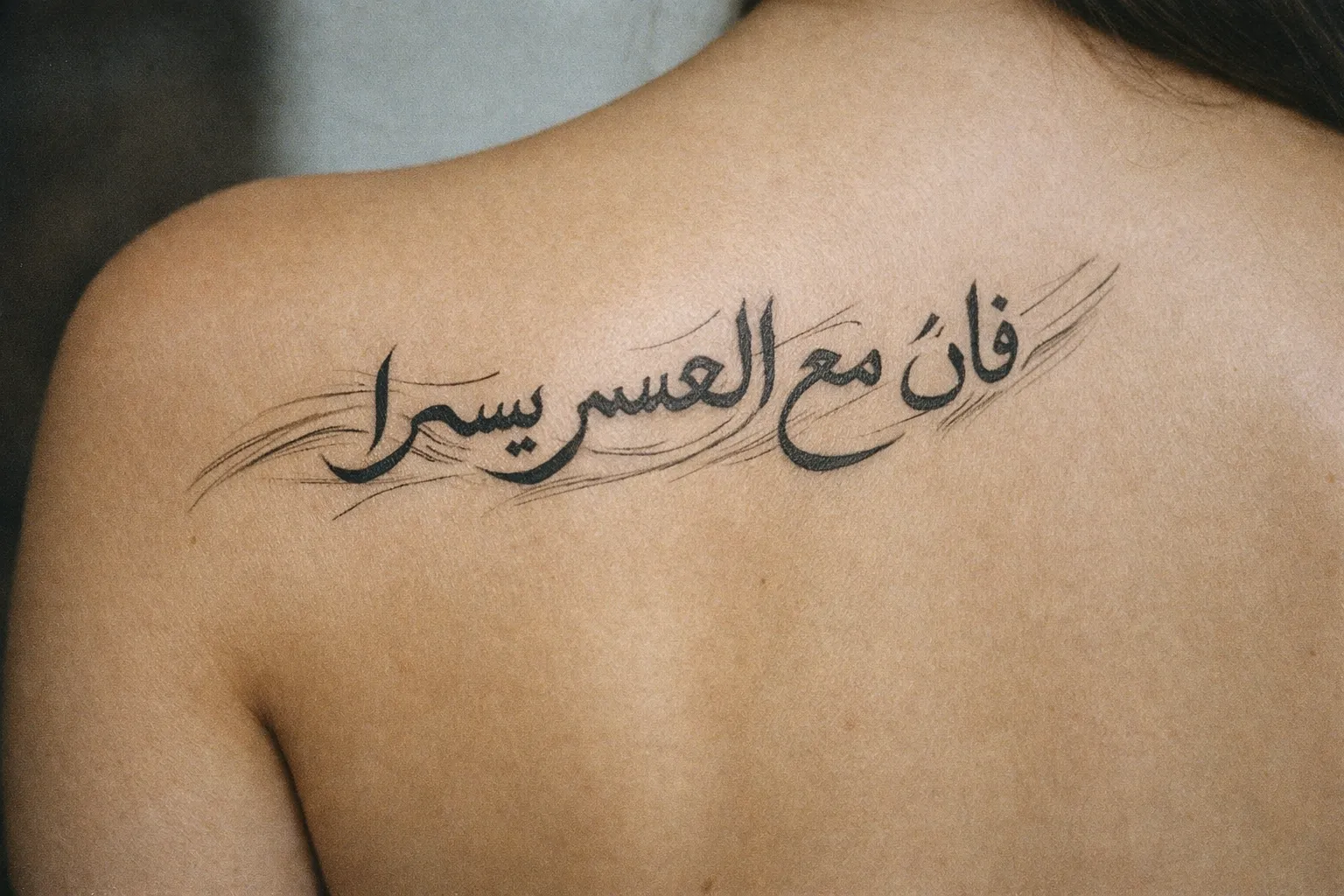 A person with an Arabic script tattoo on their upper back.