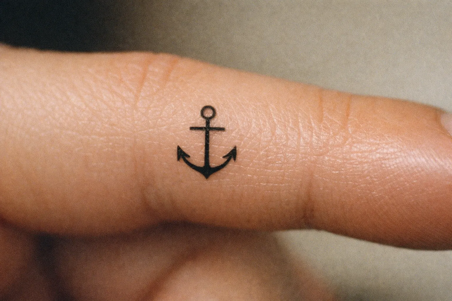 Small anchor tattoo on forearm, close-up showing scale and detailing