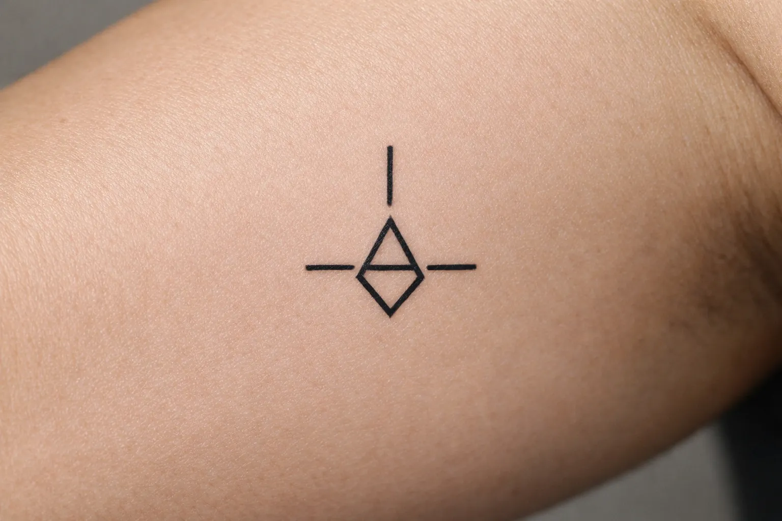 A geometric symbol tattoo is visible on a person's inner arm.