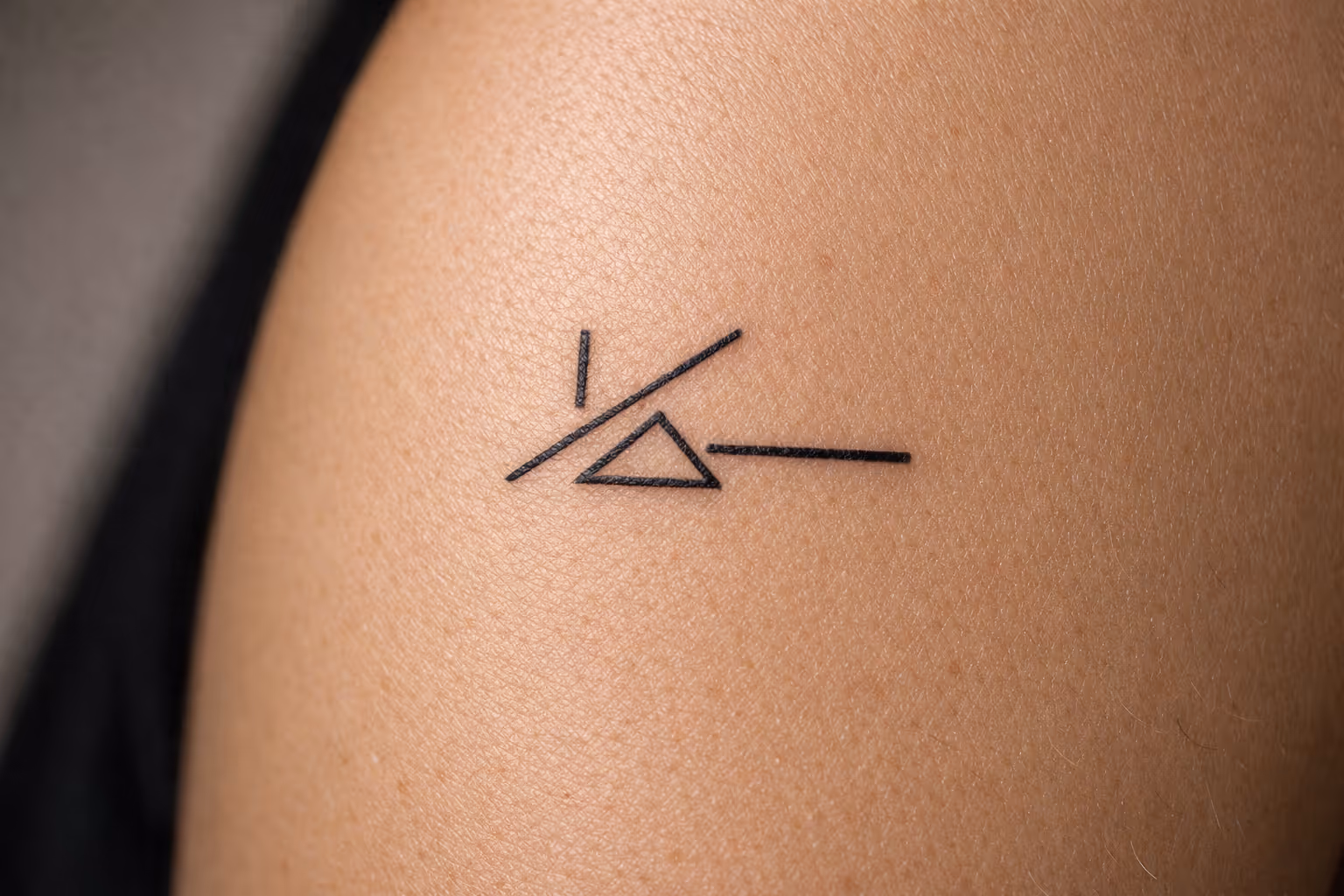 A geometric linework tattoo on a person's upper arm.