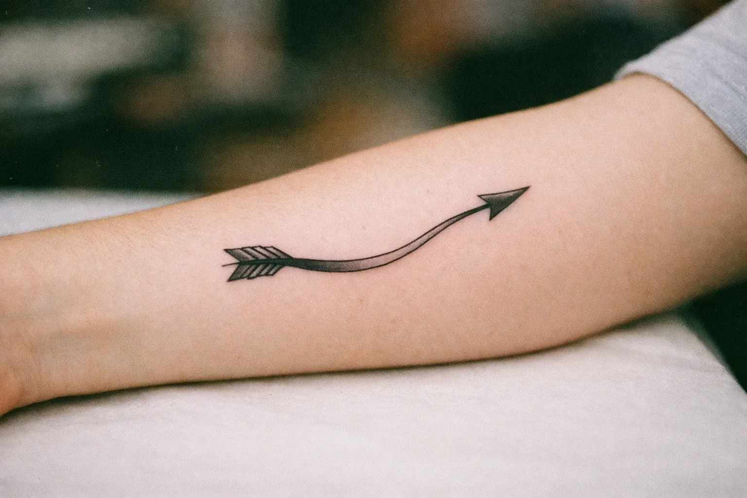 Forearm with curved arrow tattoo bending to symbolize change in direction