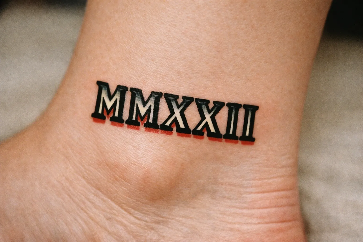 A roman numeral MMXXII tattoo on the side of an ankle.