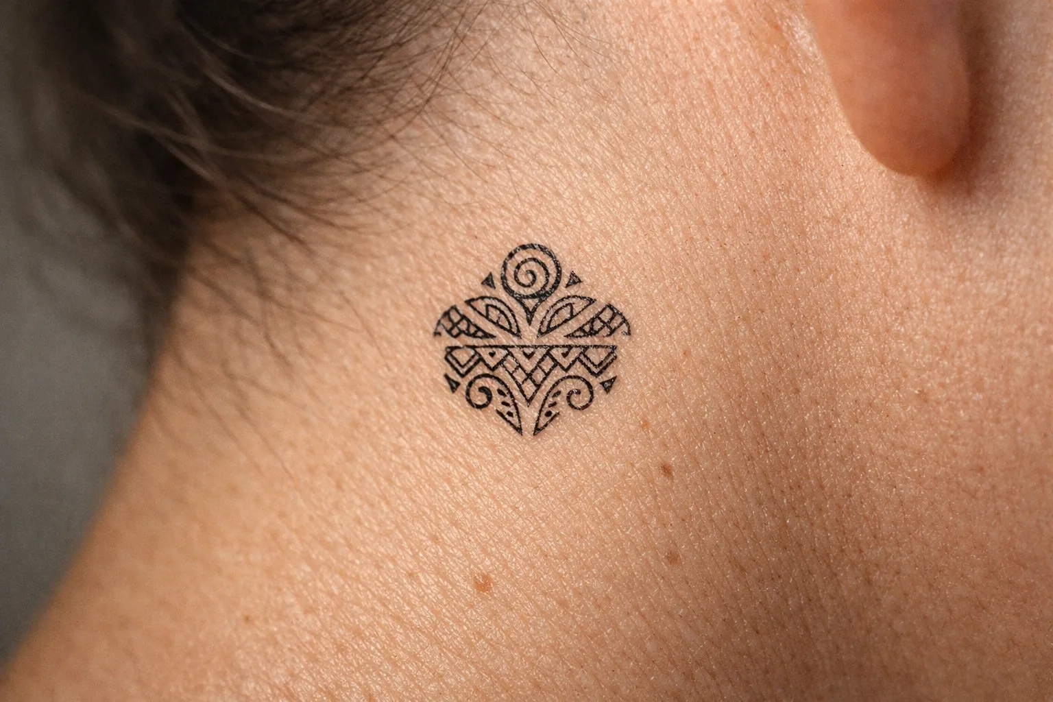 A geometric Marquesan-style tattoo on the back of a person's neck.