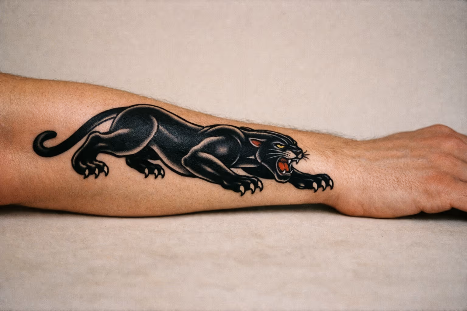 Editorial close-up of a crawling Black Panther tattoo on forearm, showing bold linework and deep blacks