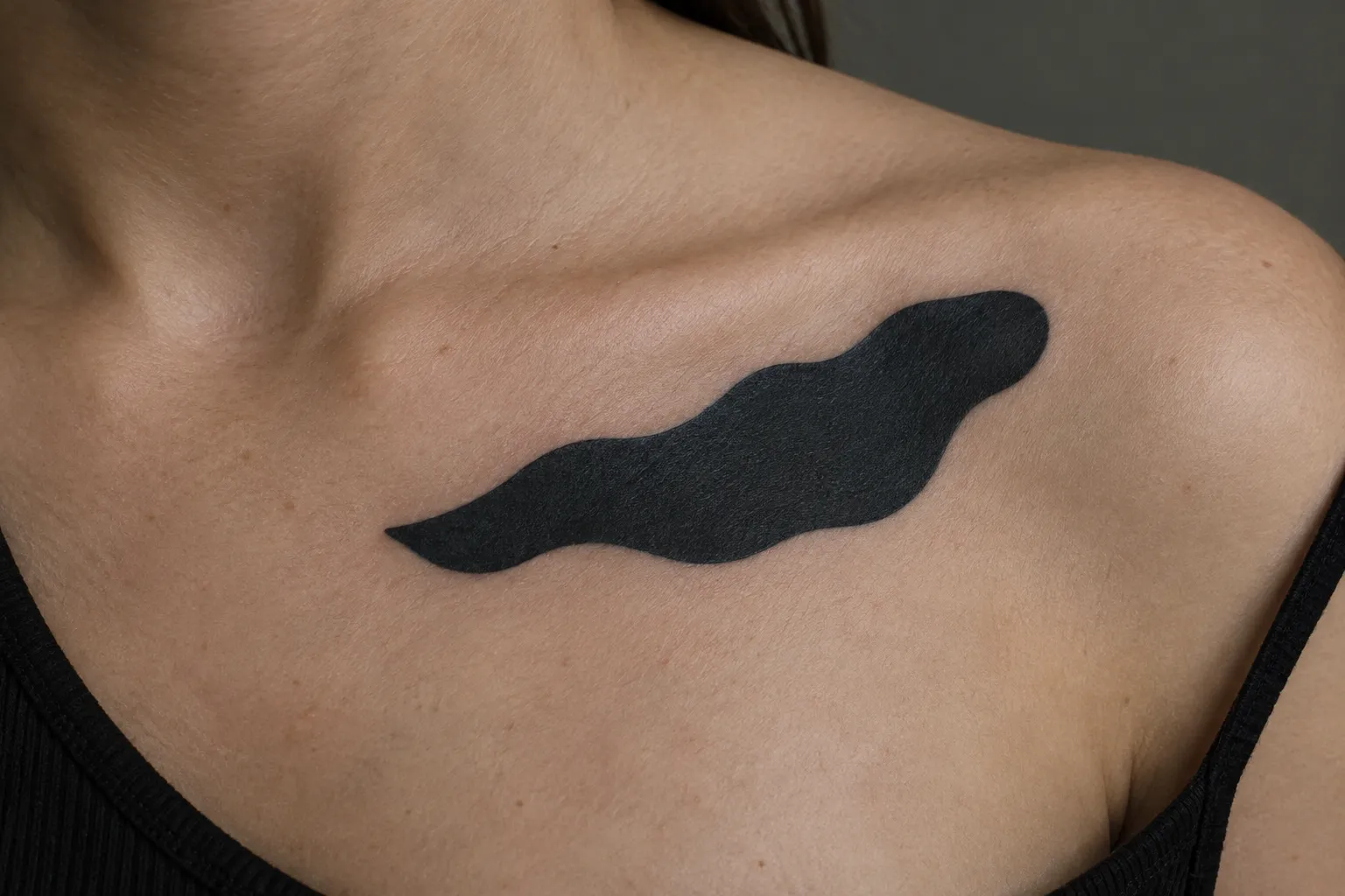 A person with a solid black tattoo across the upper chest and shoulder.