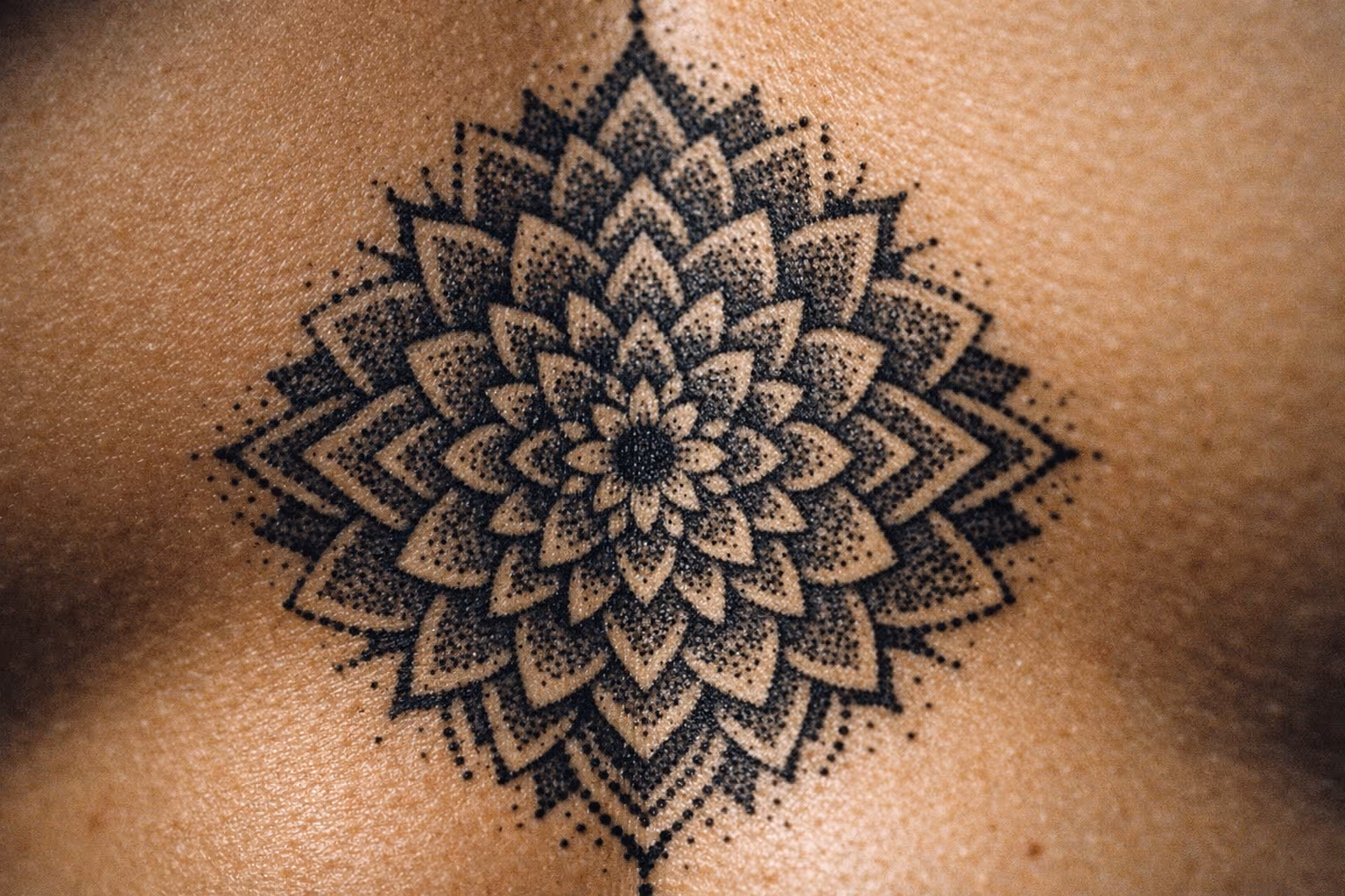 A person with a large black geometric flower tattoo across their chest.
