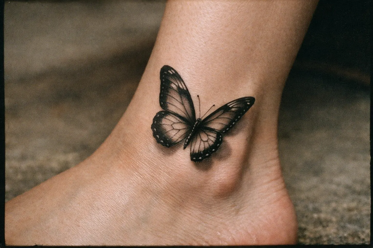 A realistic butterfly tattoo is inked on the side of a person's ankle.