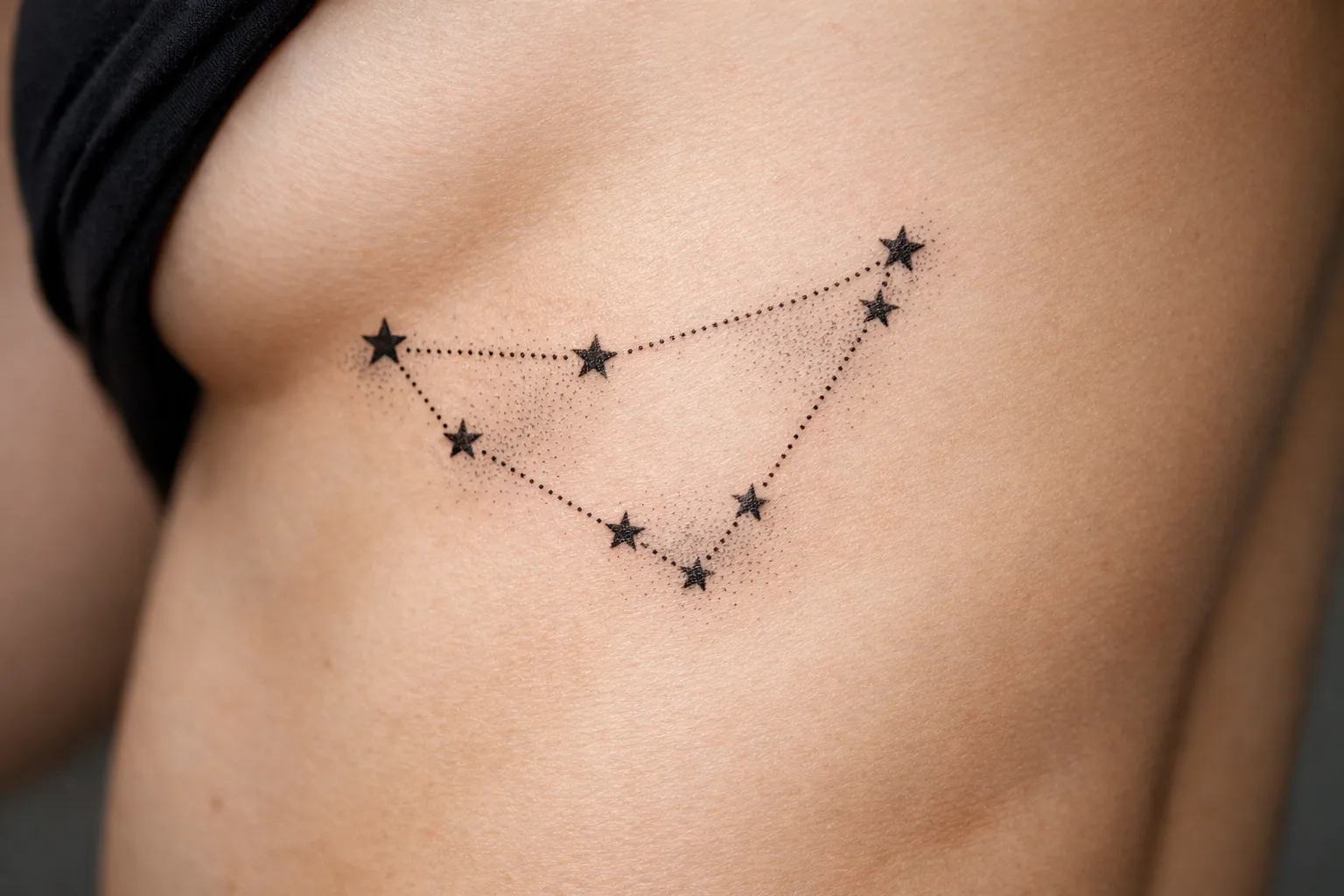 A star constellation tattoo is inked on the side of a person's torso.