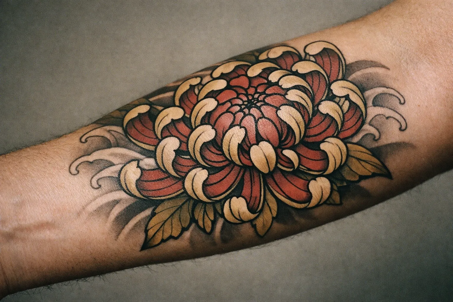 Japanese-inspired chrysanthemum tattoo on forearm with bold outlines