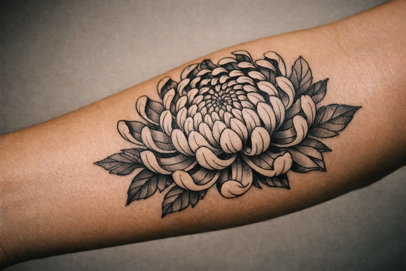 Editorial close-up of a chrysanthemum tattoo on forearm