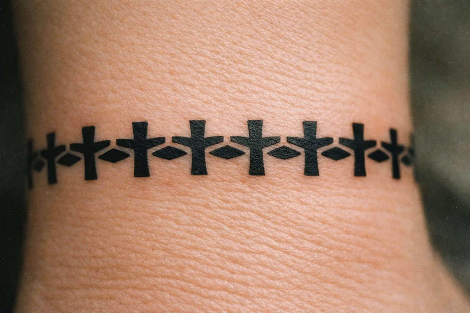 Large, bold cross tattoo on the outer forearm with thick lines