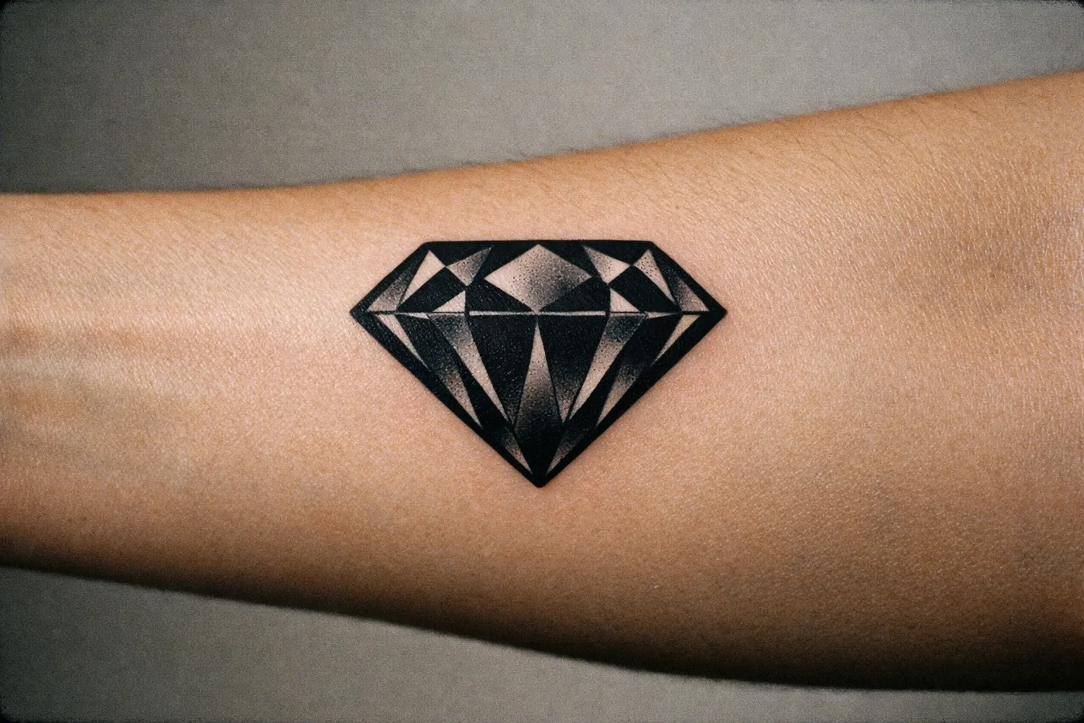 Close-up of a diamond tattoo on forearm with bold black lines
