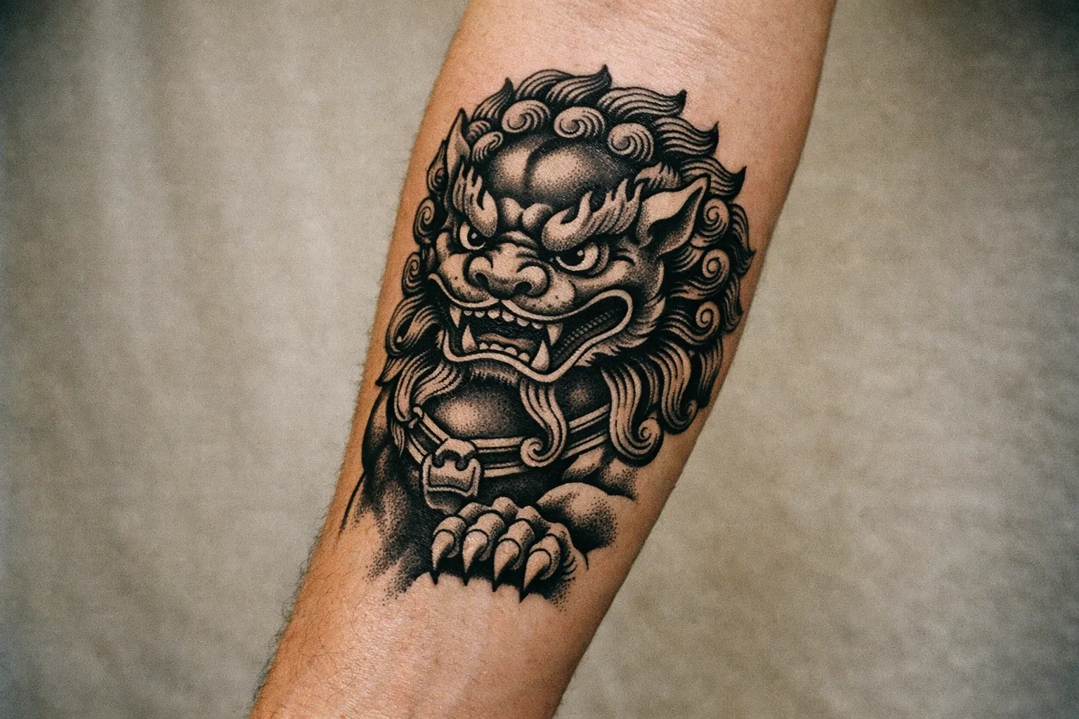 Forearm Foo Dog (guardian lion) tattoo with bold linework and shading