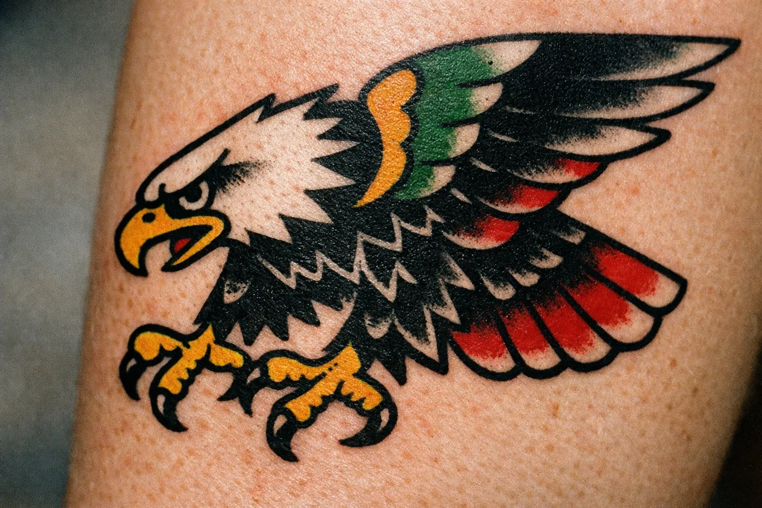 Forearm traditional eagle tattoo with heavy outlines and saturated colors showing classic US traditional style