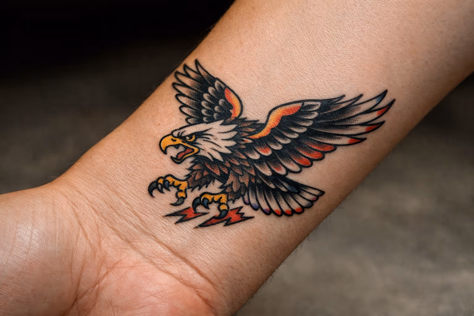 A person's inner forearm with a bold eagle tattoo featured in the center.