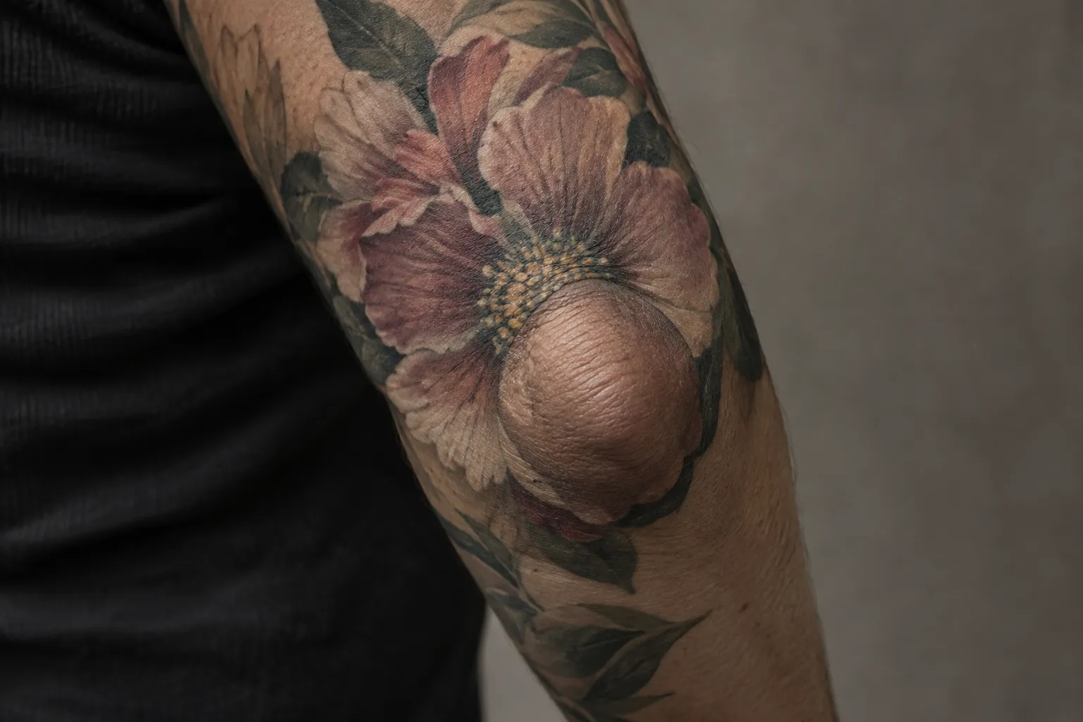 A floral tattoo wraps around the point of a bent elbow, leaving the bony tip itself bare.