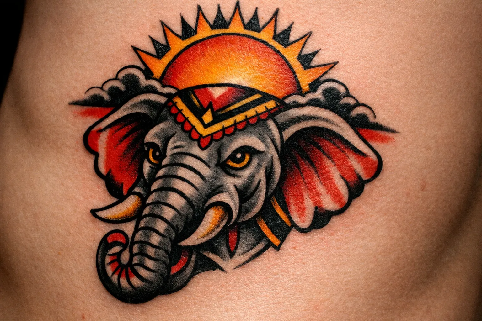 A colorful elephant head tattoo with a sun design on a person's skin.