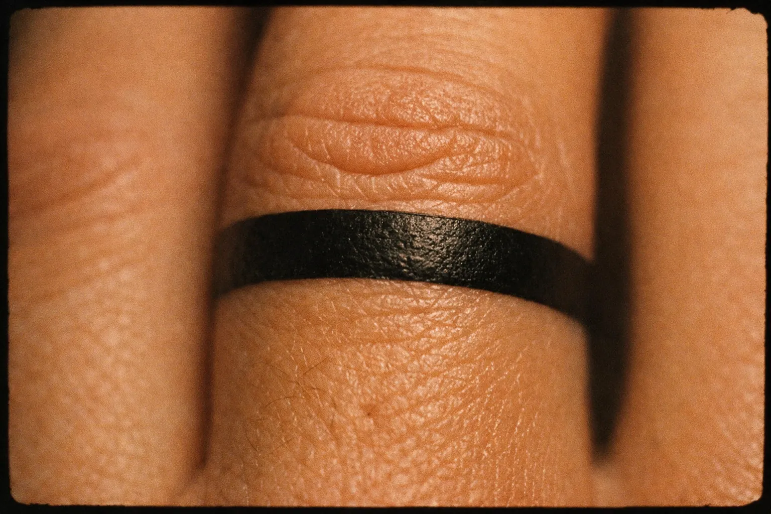 A finger with a solid black band tattoo around the middle knuckle.