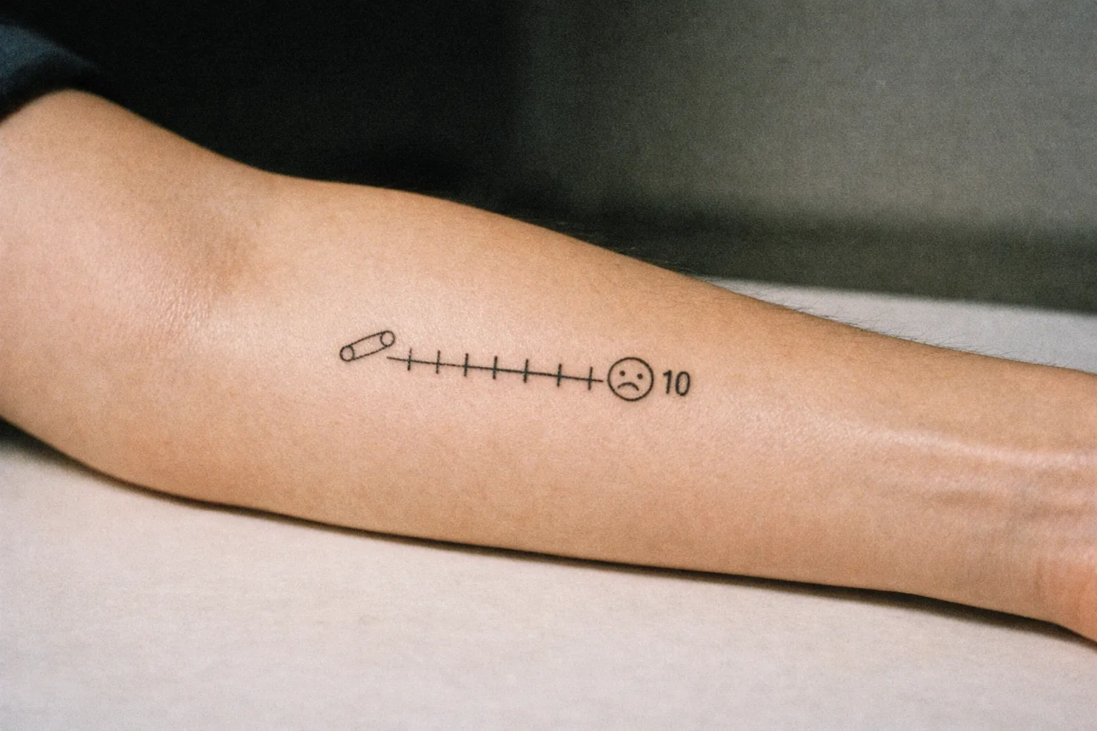 Forearm resting on a clean studio surface, forearm tattoo visible, calm editorial mood