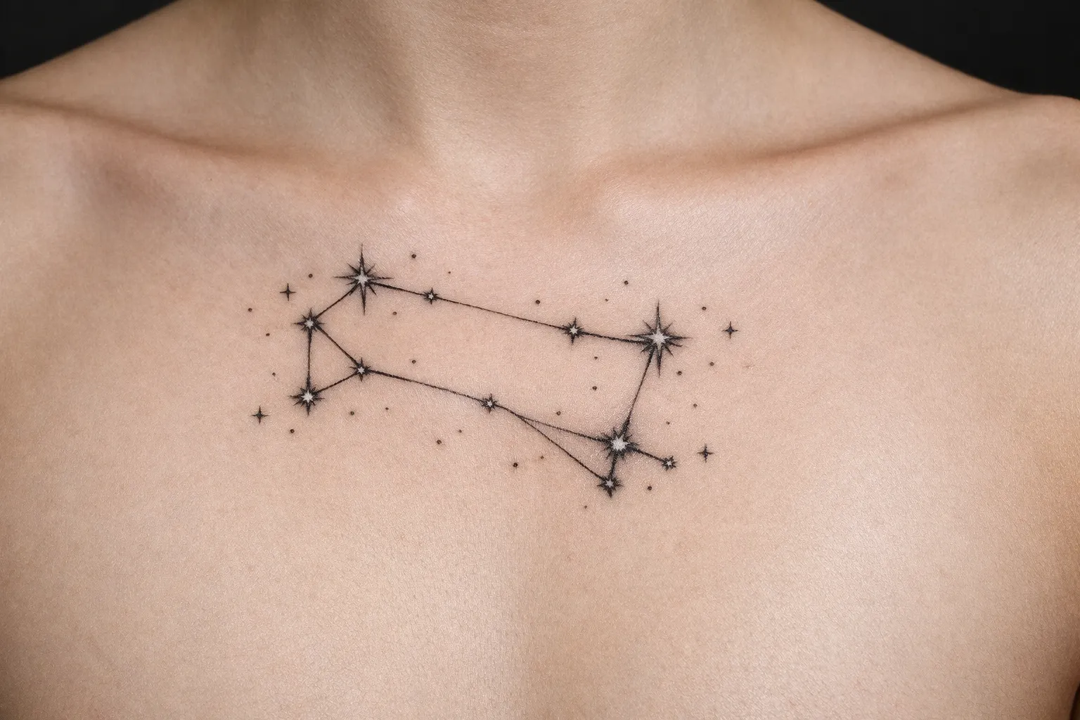 A Gemini constellation tattoo is inked on the upper chest of a person.
