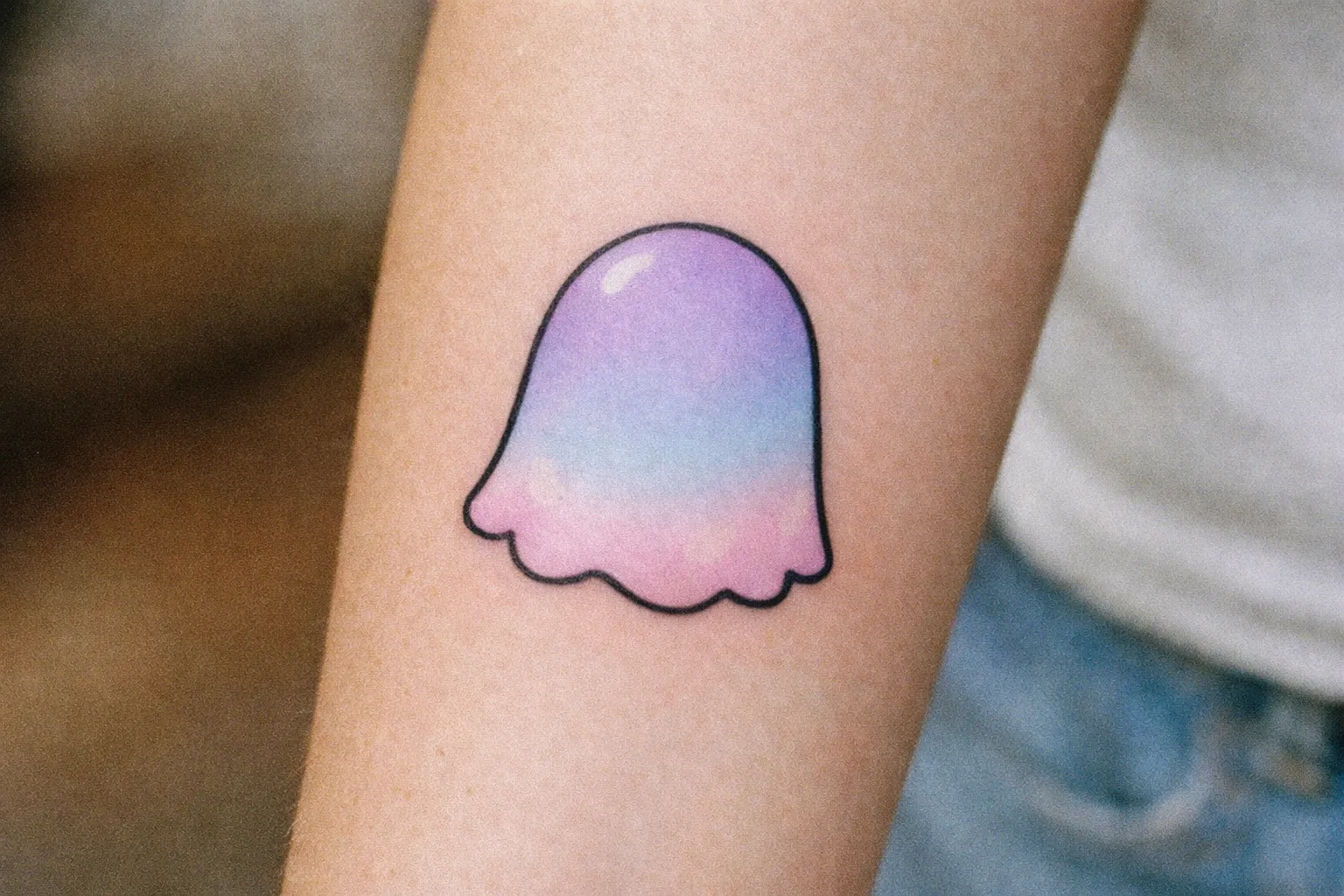 Pastel ghost tattoo on forearm with soft shading and rounded form