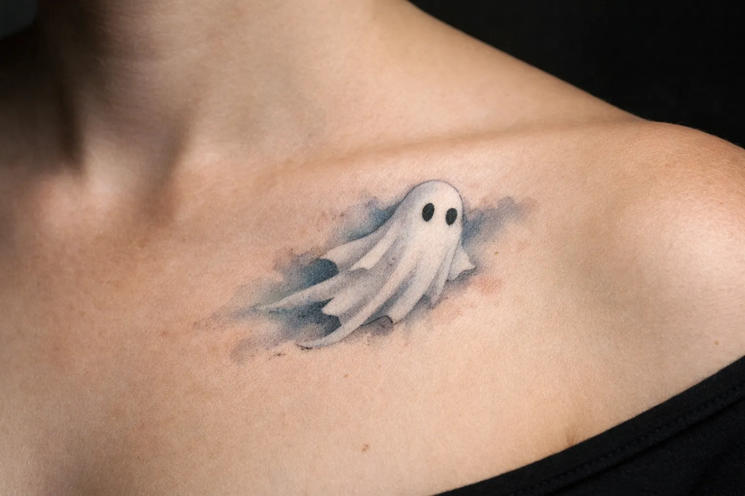 A simple ghost tattoo is inked on the upper chest near the collarbone.