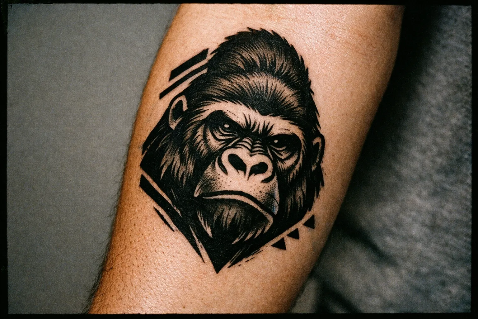 Close-up forearm featuring a gorilla tattoo in blackwork with subtle geometric accents
