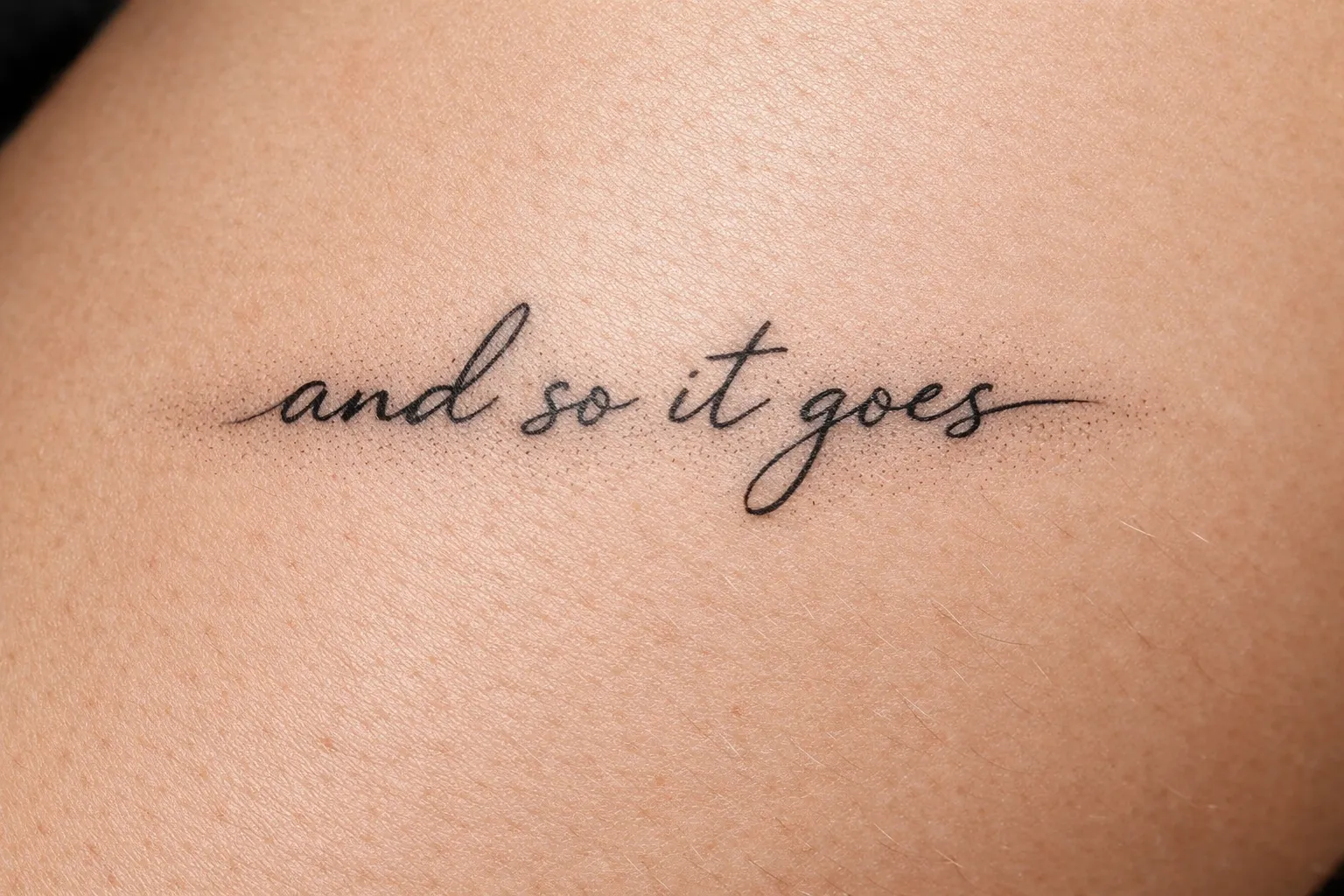 A script tattoo reading 'and so it goes' on a person's skin.