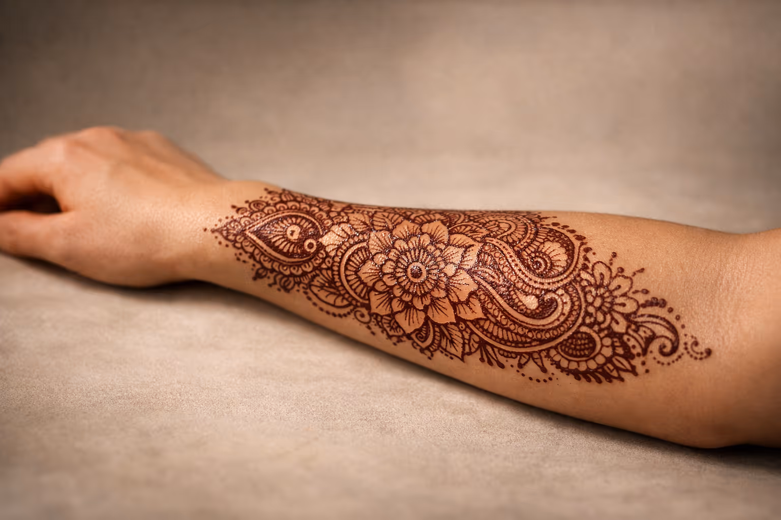 Editorial hero image: healed henna on the inner forearm with intricate floral and paisley pattern in natural brown.