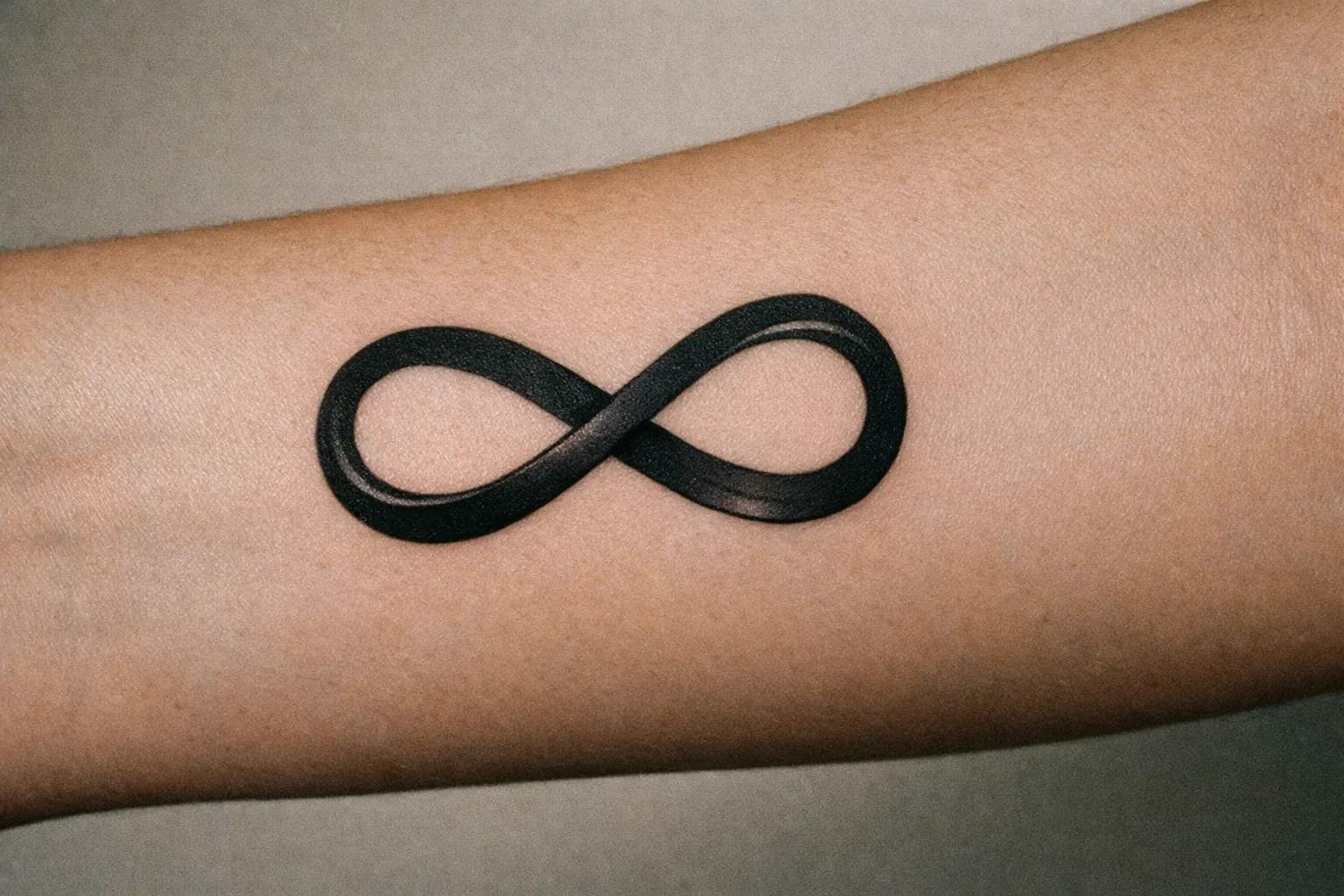 Close-up of a bold black infinity tattoo on forearm with crisp linework