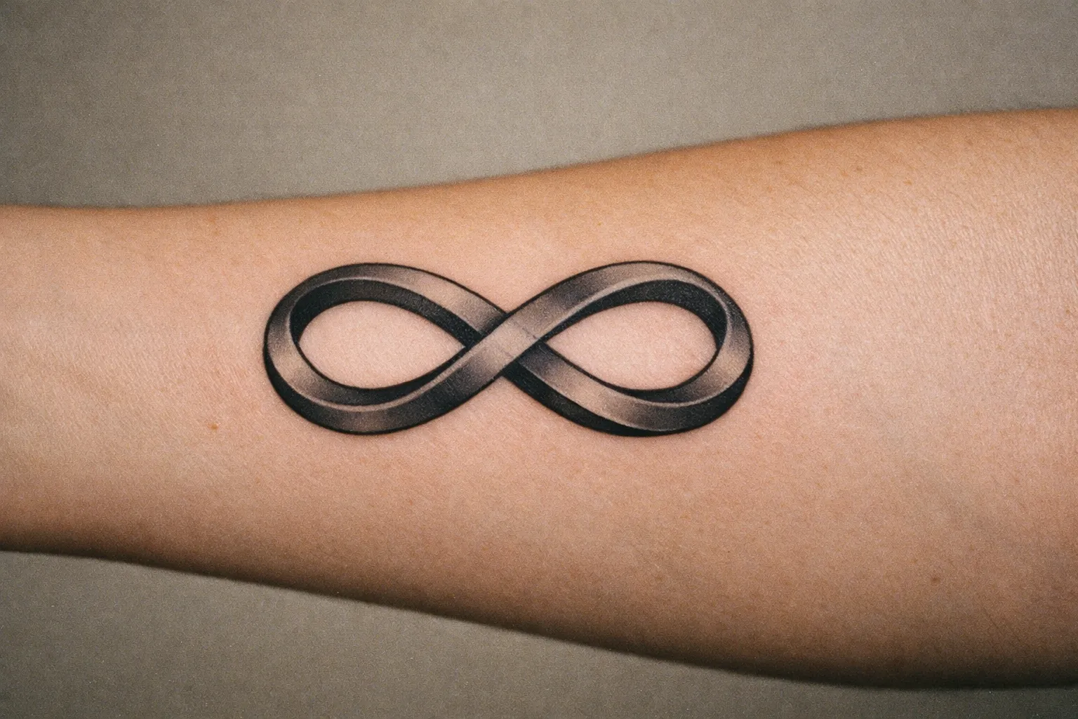Double infinity tattoo on forearm with two interlocking loops