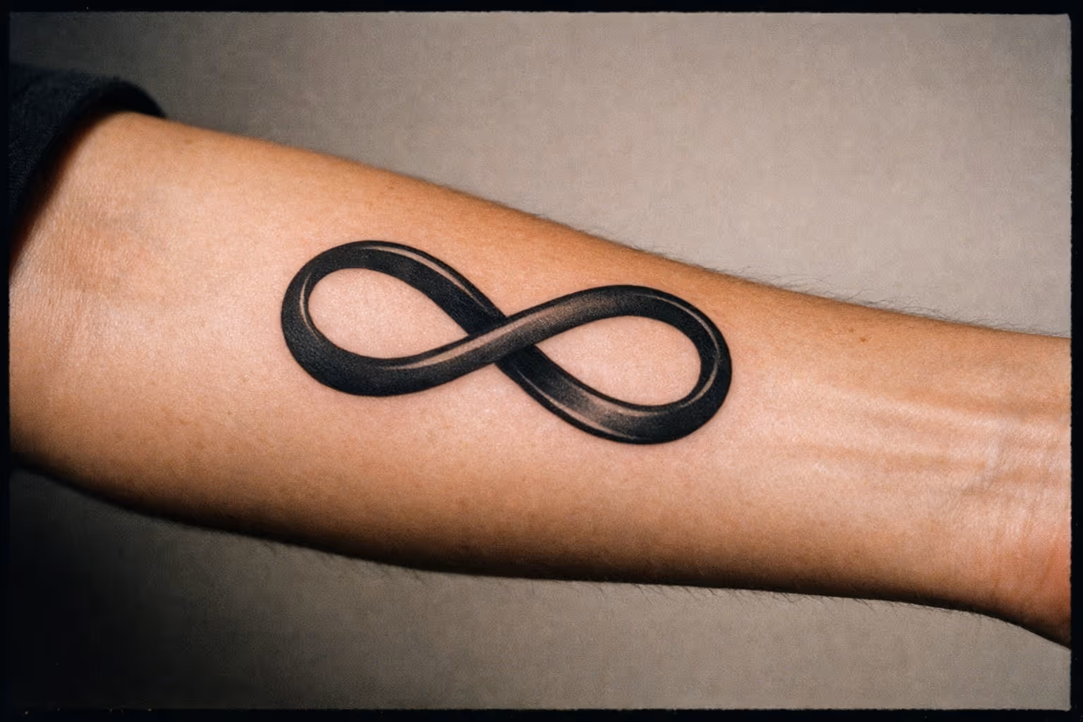 Editorial close-up of infinity tattoo on forearm