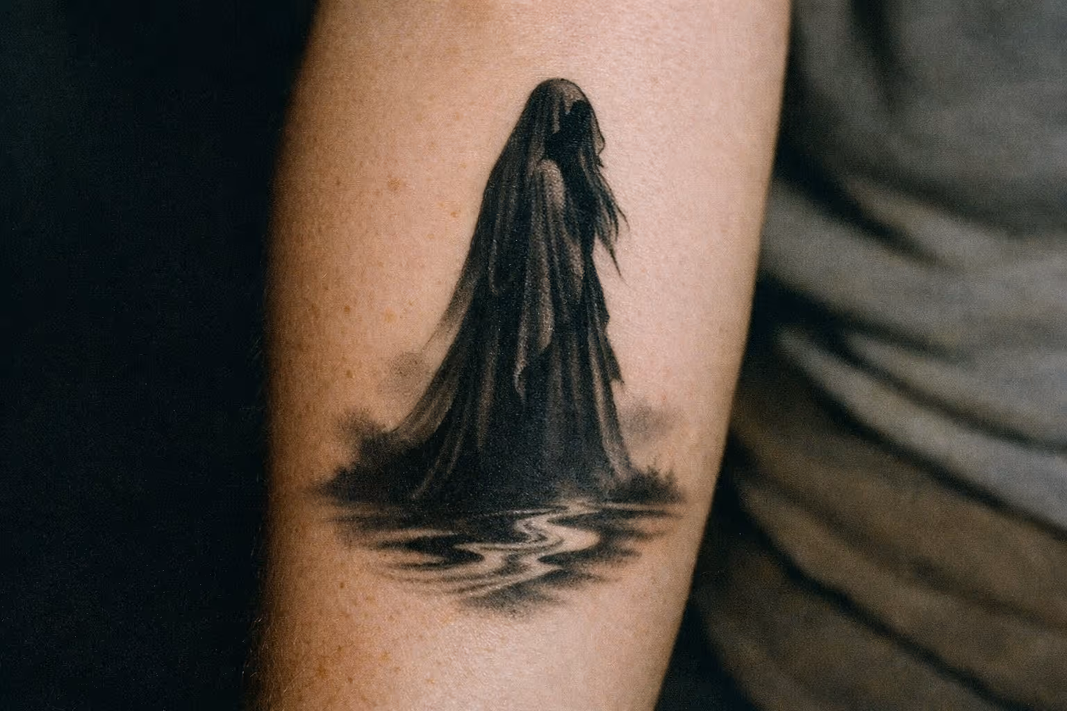 Editorial close-up of La Llorona tattoo on forearm, showing a veiled figure with flowing lines and subtle river motif.
