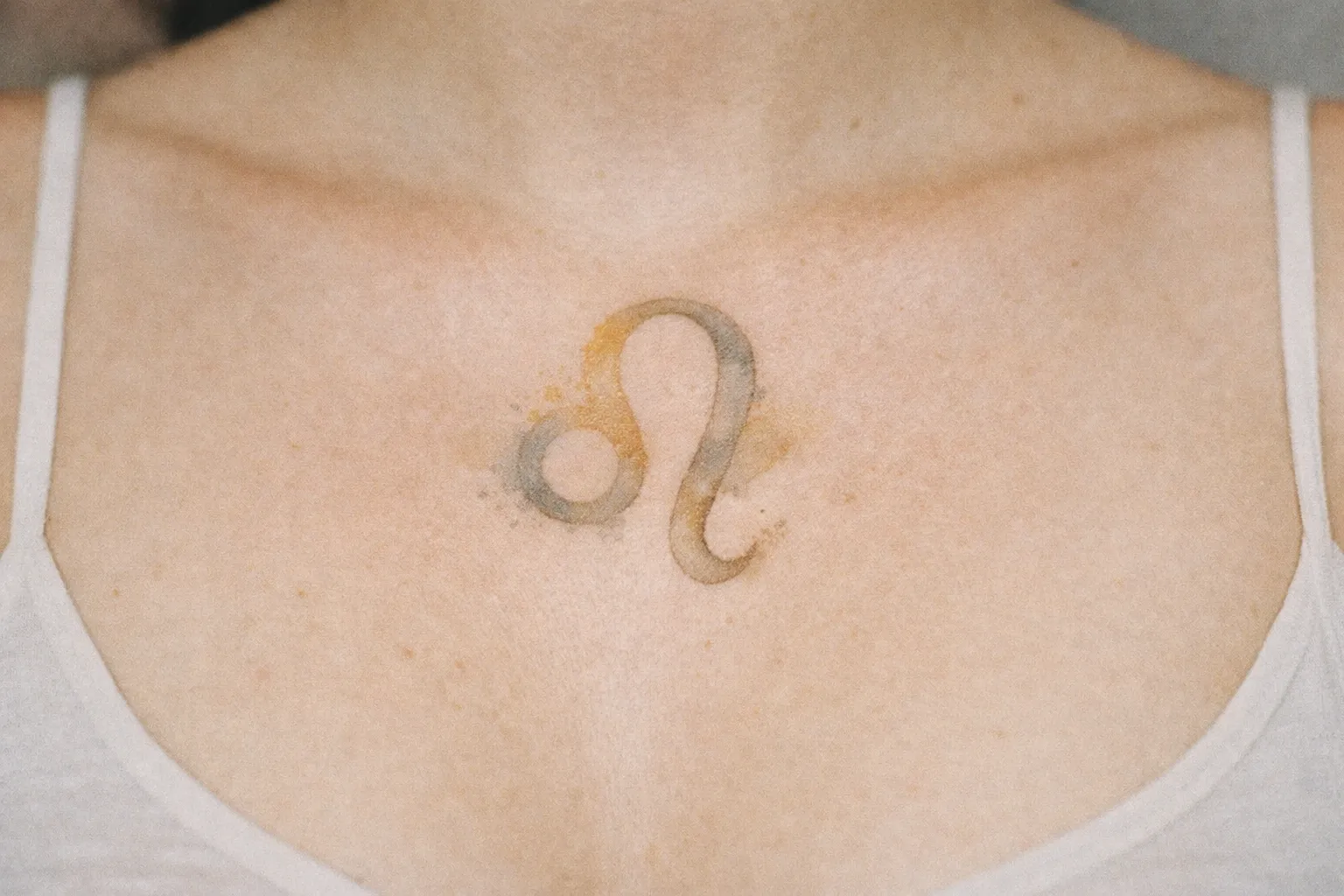 A person with a Leo zodiac symbol tattoo on their upper chest.