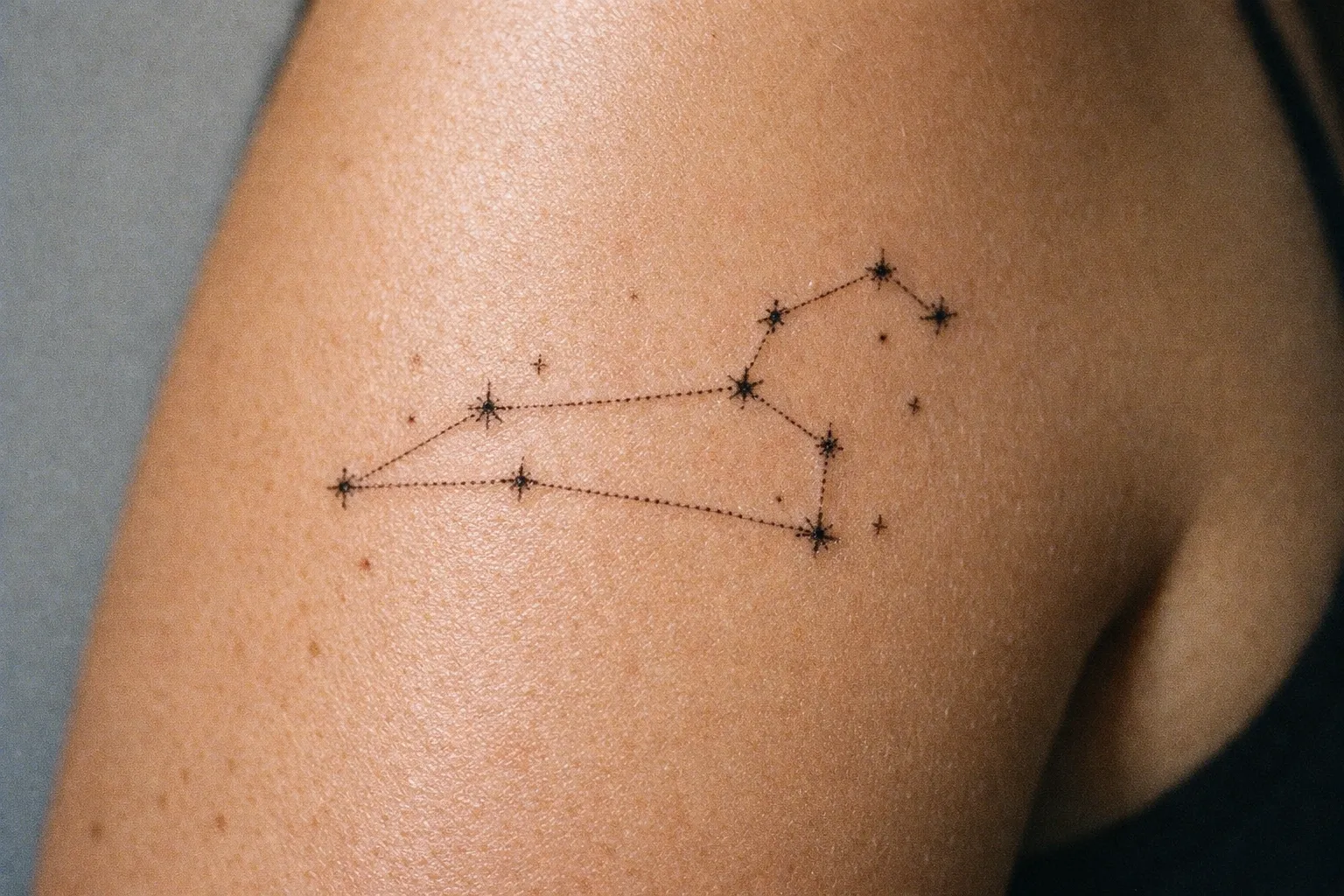 A Leo constellation tattoo is inked on a person's upper arm.