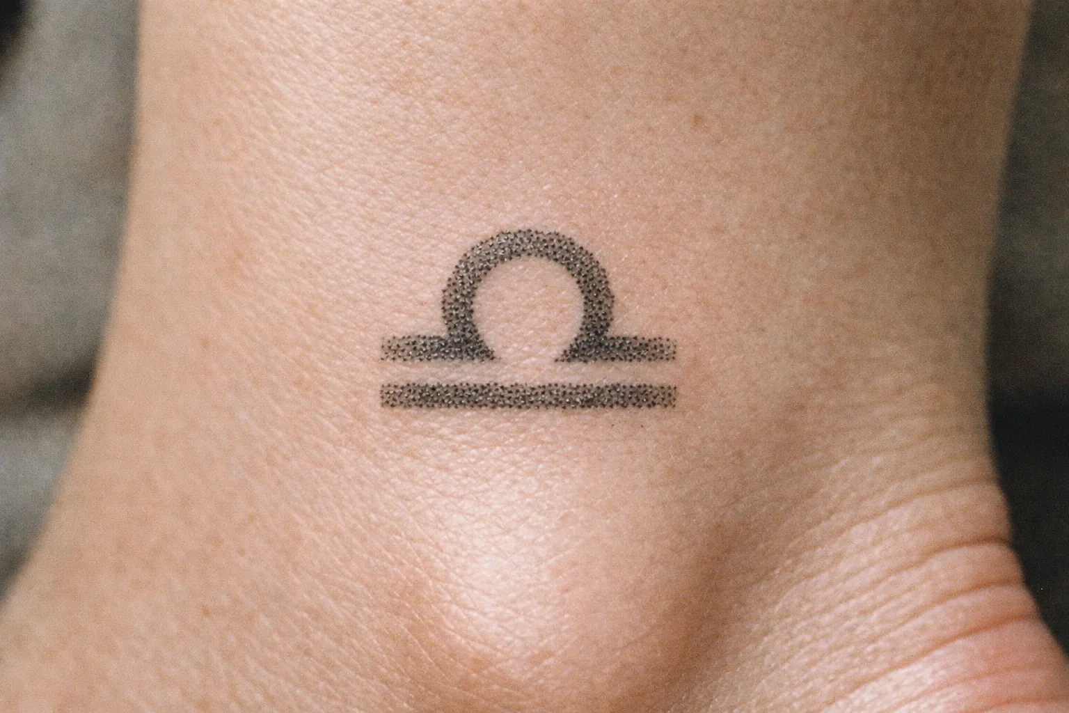 A Libra zodiac symbol tattoo on the top of a person's foot.