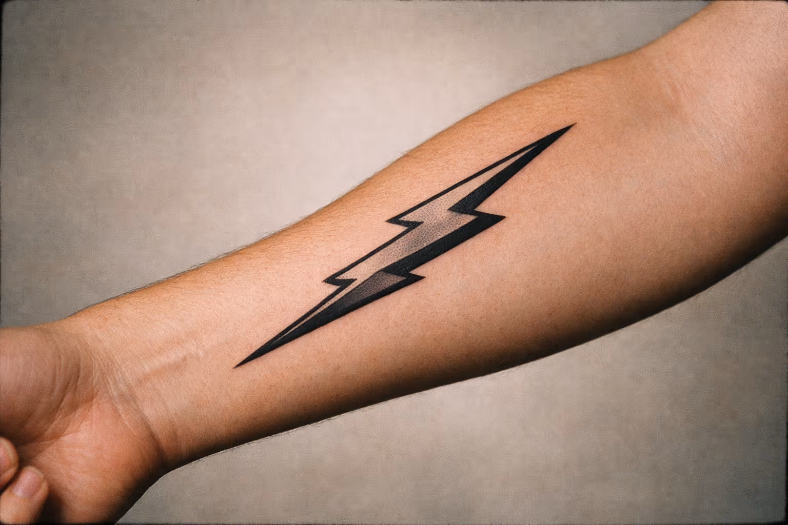 Hero image: single lightning bolt tattoo along a forearm in editorial studio lighting
