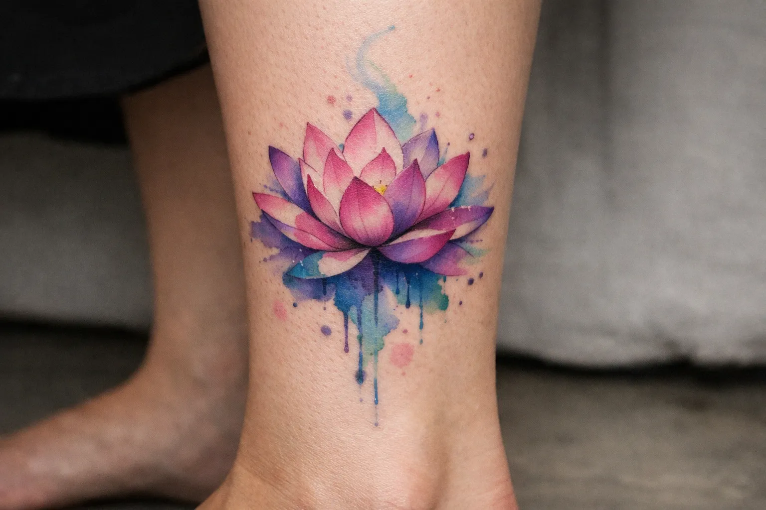 A colorful lotus flower tattoo on a person's lower leg.