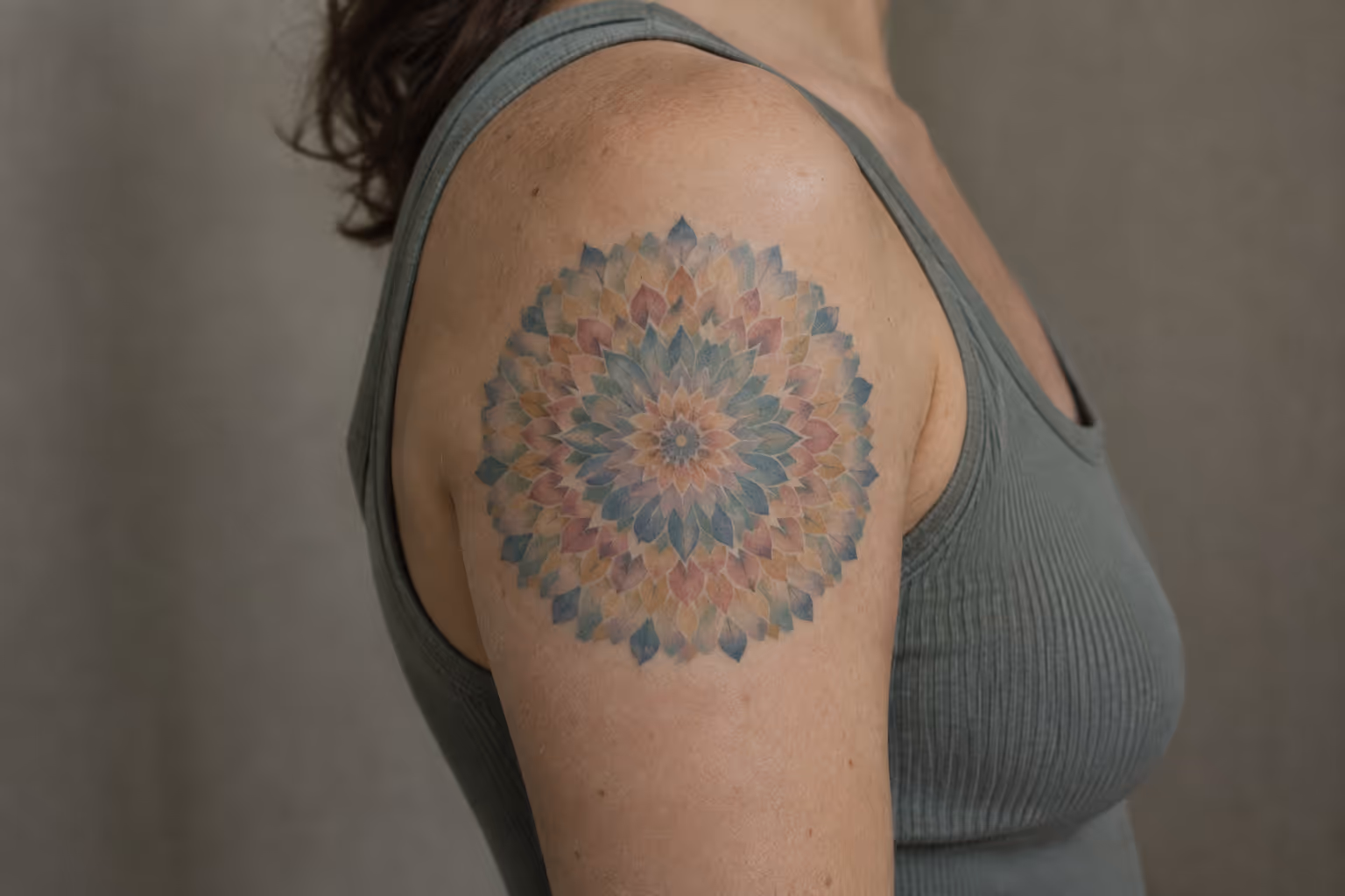 A woman with a colorful mandala tattoo on her upper arm.