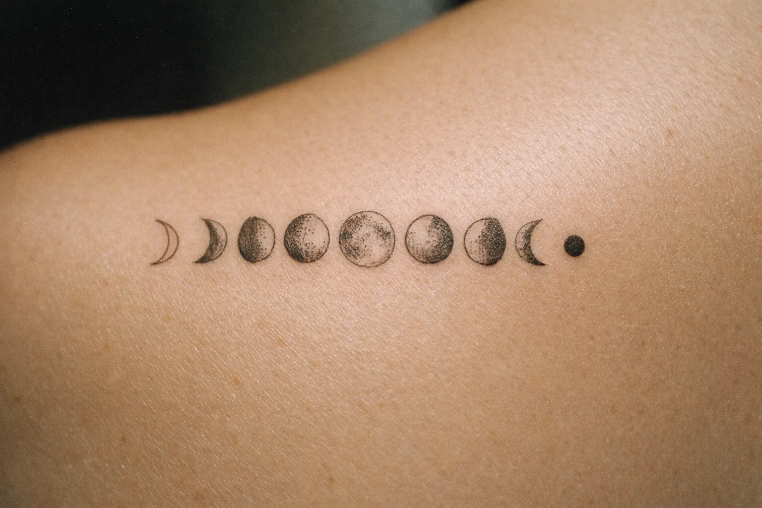 A tattoo of the moon phases is inked across the upper back.