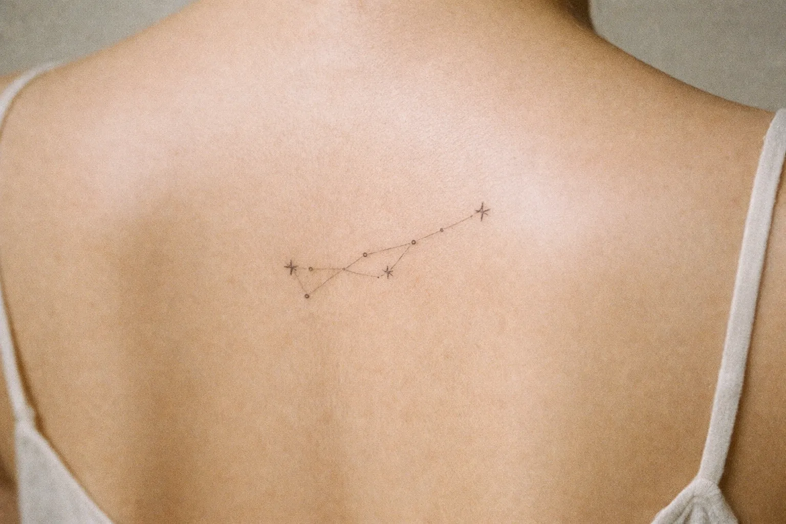 A person with a delicate constellation tattoo on their upper back.