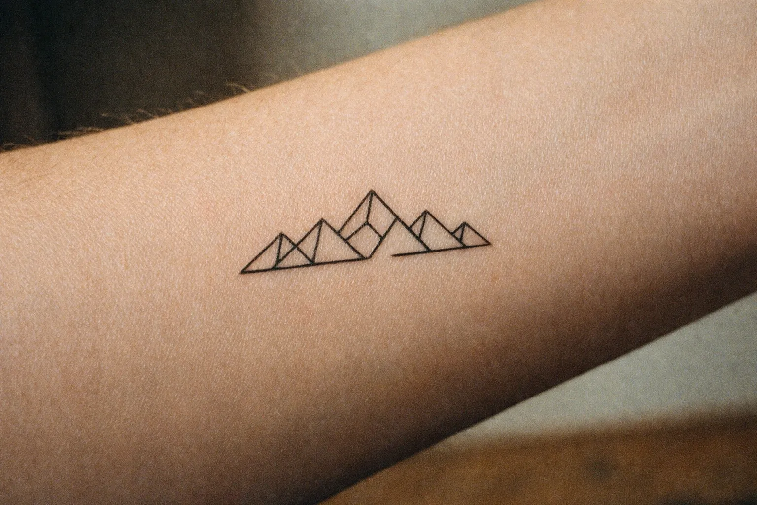 Forearm with a small geometric mountain range tattoo
