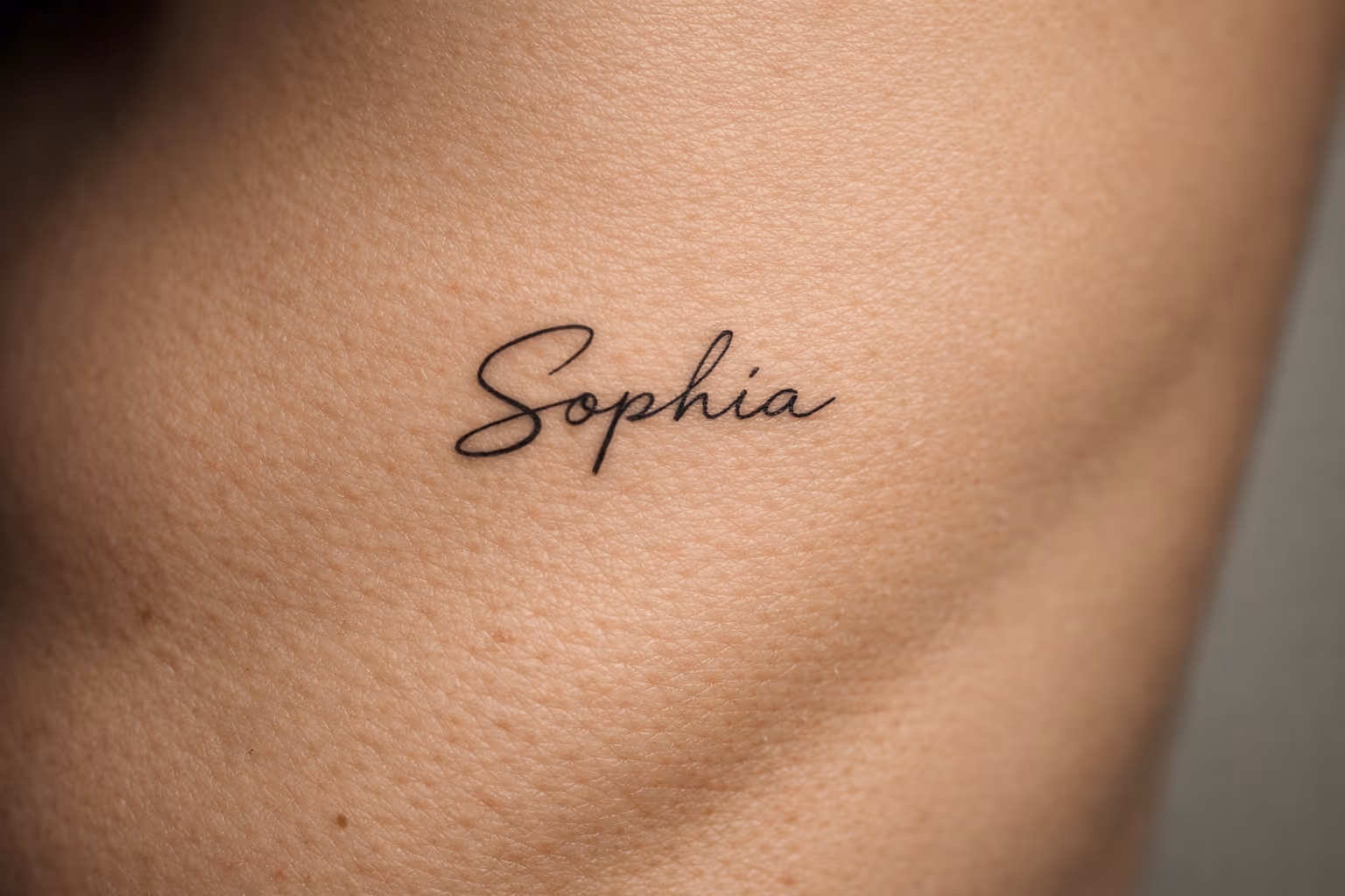 A close-up of skin with a tattoo reading 'Sophia' in black script.