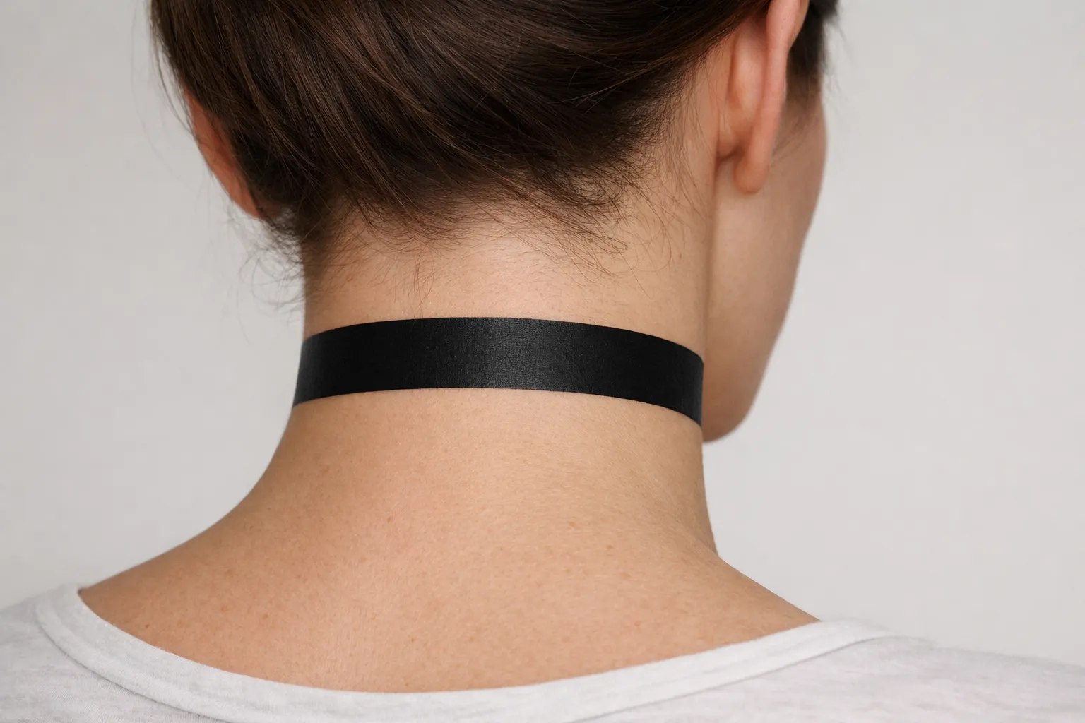 A person with a solid black band tattoo around their neck, viewed from behind.