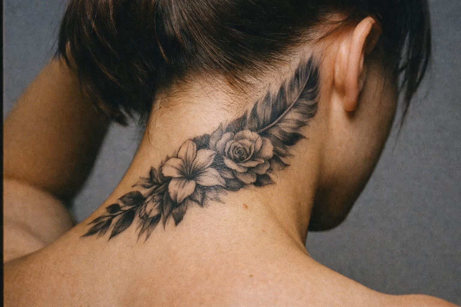A person with a detailed floral tattoo on the back of their neck and upper shoulder.
