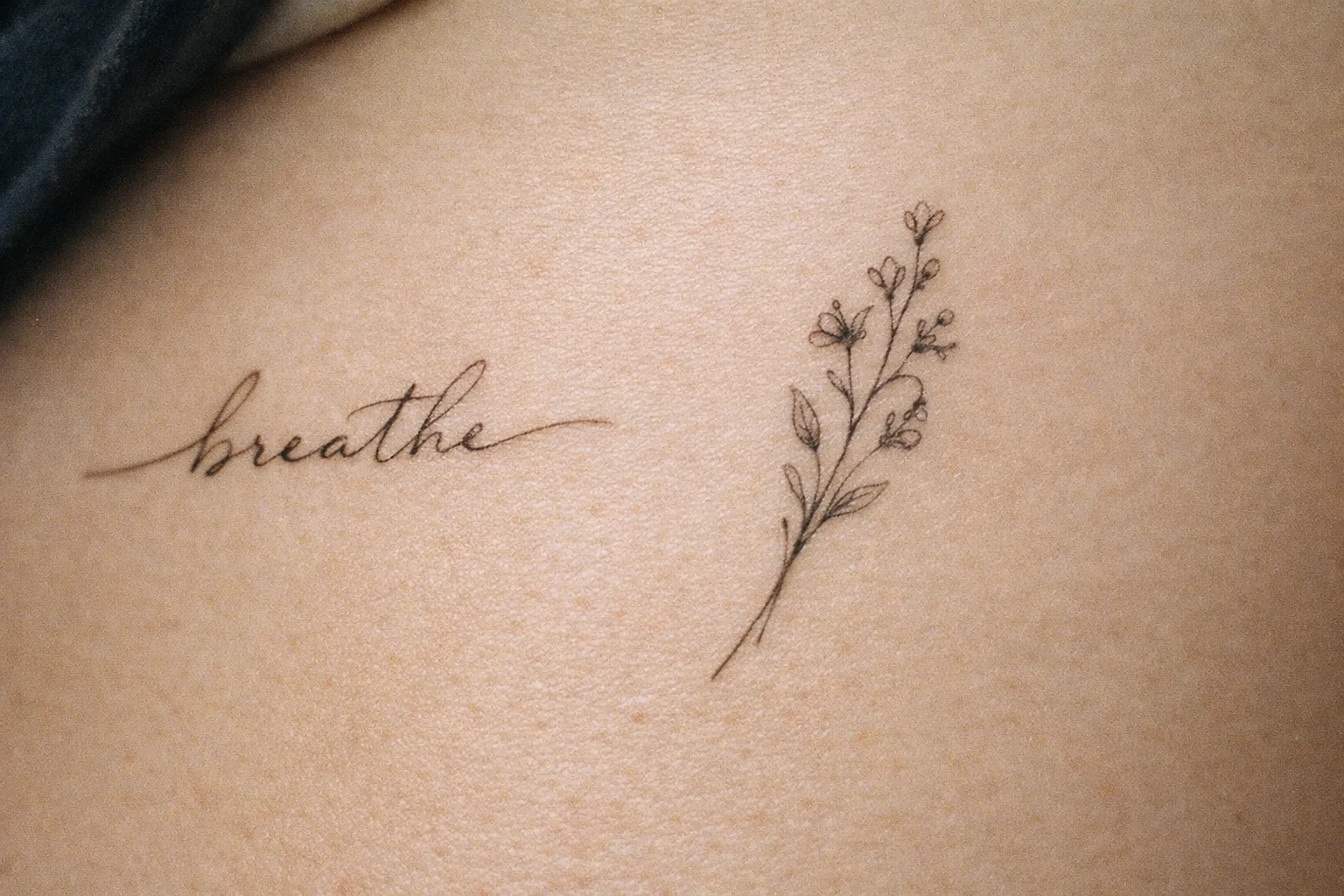 A close up of a rib with a script and floral tattoo on bare skin.