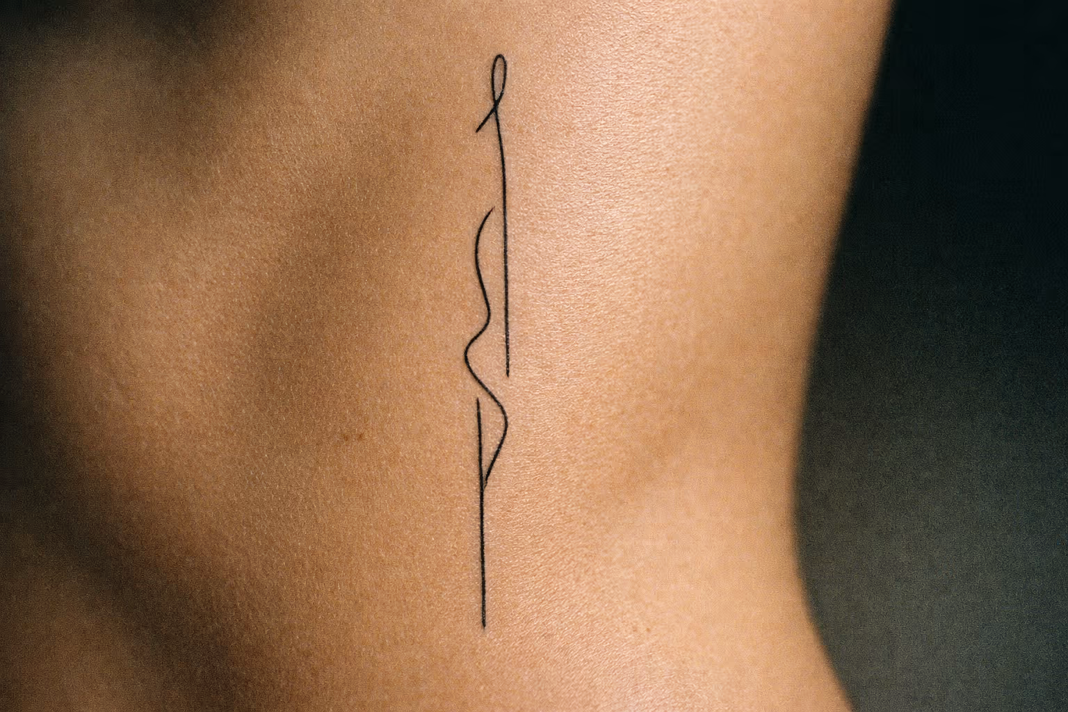 A minimalist line tattoo on a person's ribcage.