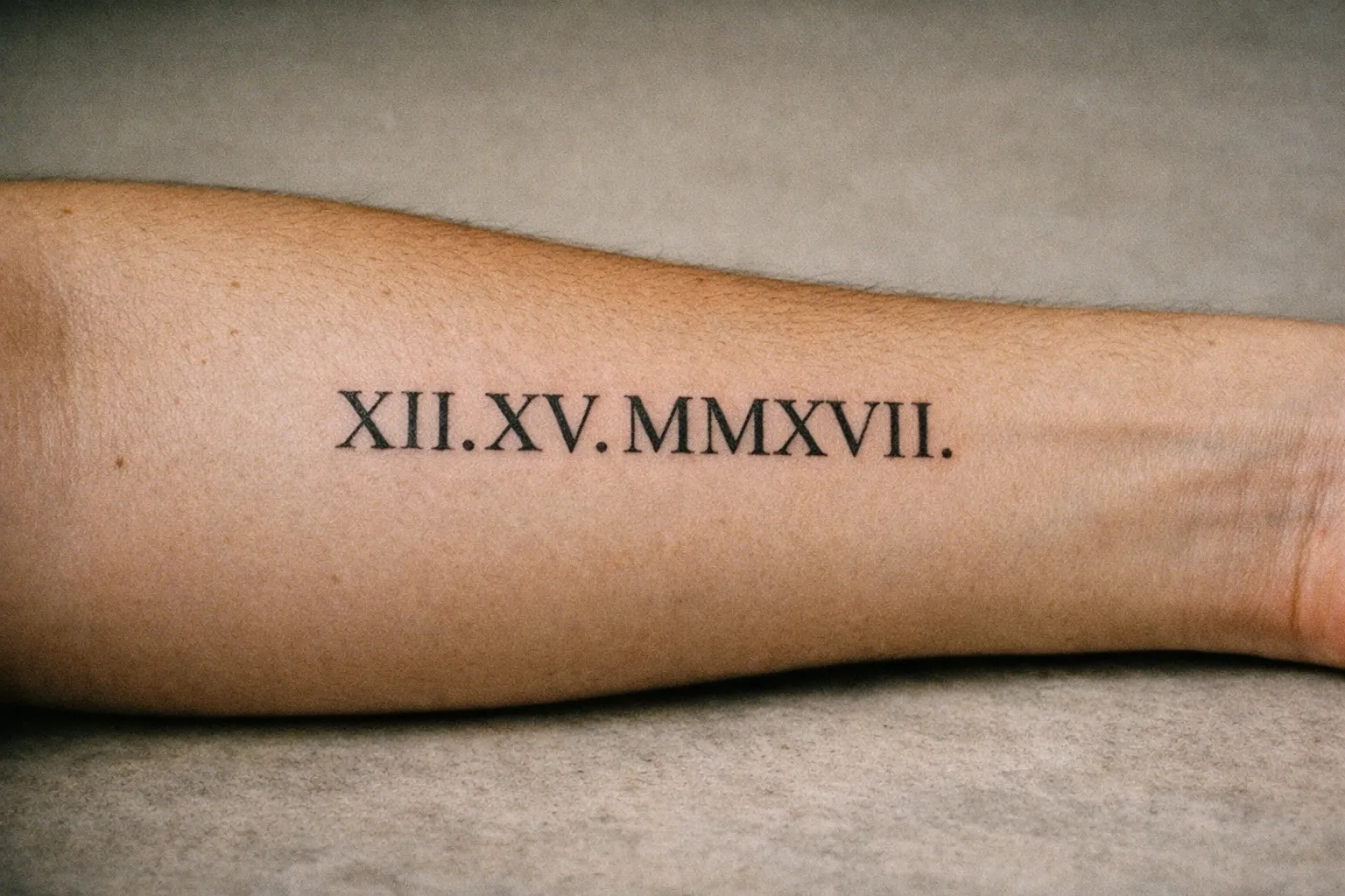 Close-up of a healed black Roman numeral tattoo along the inner forearm